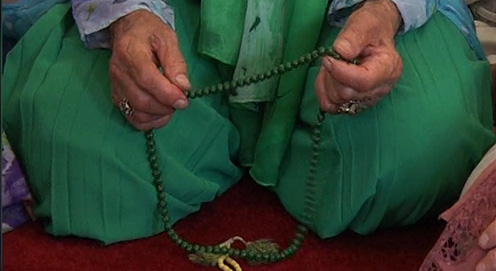 Woman in green with prayer chain